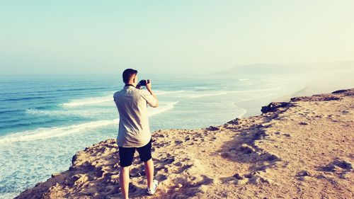 Rear view of man photographing on beach