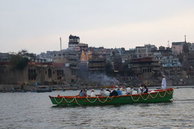 People on boats in river against buildings in city