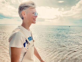 Mature woman looking at sea shore against sky