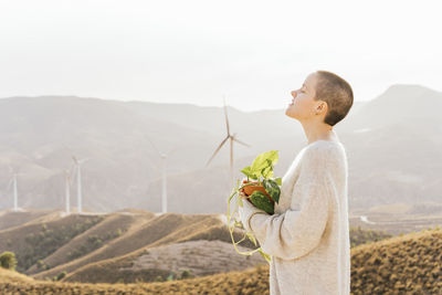 Side view of man standing on mountain against sky