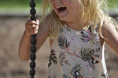 Midsection of cheerful girl on swing