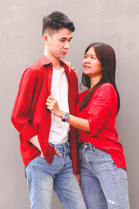 Smiling friends standing against wall