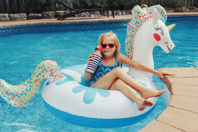 Portrait of cute girl sitting on inflatable in swimming pool