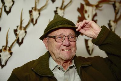 Close-up of man looking away against antlers on wall