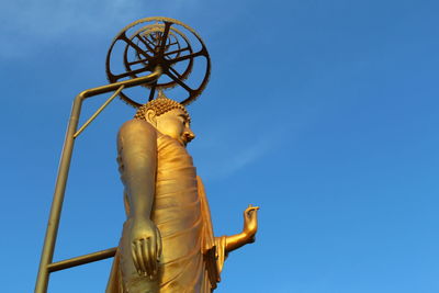 Low angle view of buddha statue against blue sky