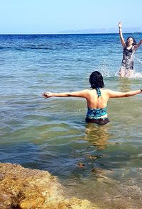 Rear view of friends in sea against sky