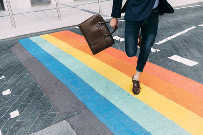 Businessman holding briefcase while running on multi colored markings on street