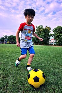 Boy playing soccer ball on grass