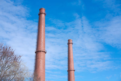 Two tall abandoned industrial chimney pipes against blue sky. chimneys