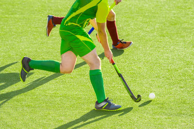 Low section of men playing hockey on field