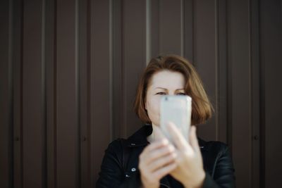 Portrait of beautiful woman standing against wall