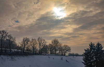 Snow covered field against sky during sunset