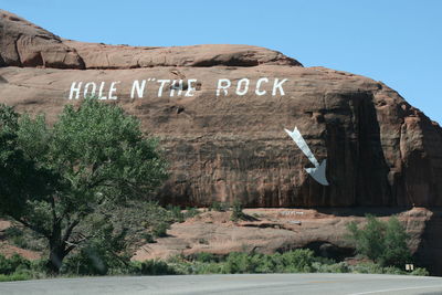 Text on rock formation against sky