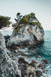 Rock formation in sea against clear sky