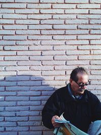 Portrait of young man standing against brick wall