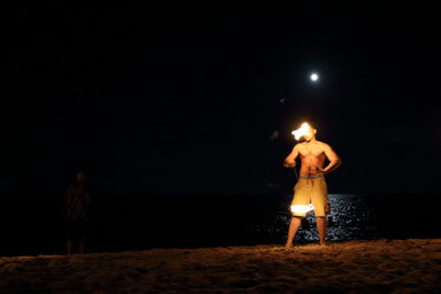 Rear view of man standing on beach against sky