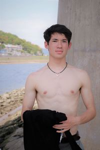 Portrait of shirtless young man standing outdoors
