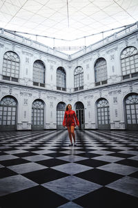 Full length of woman standing on tiled floor by building