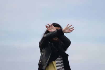 Woman with hands in front of face against clear sky