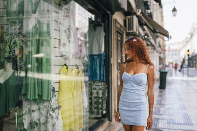 Young woman doing window shopping standing on footpath