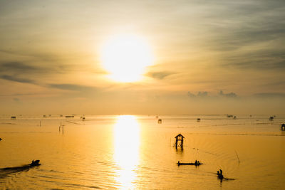 Fishing boat for small fish in the sea with sunset background, silhouette concept.