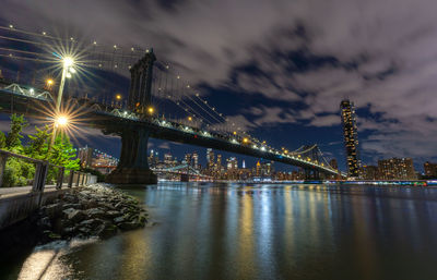 Illuminated bridge over river at night