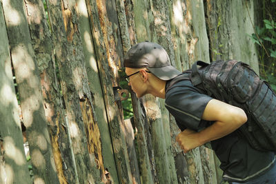 Side view of man climbing on tree trunk in forest