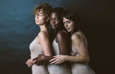 Women standing against black background