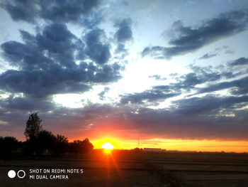 Road sign on field against sky during sunset