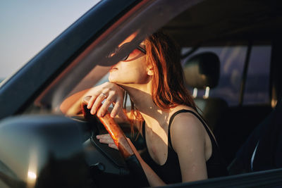 Young woman wearing sunglasses sitting in car