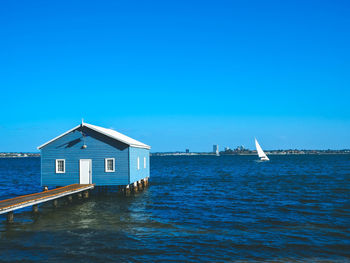 Building by sea against clear blue sky