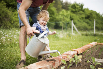 Father with his little son in the garden watering seedlings