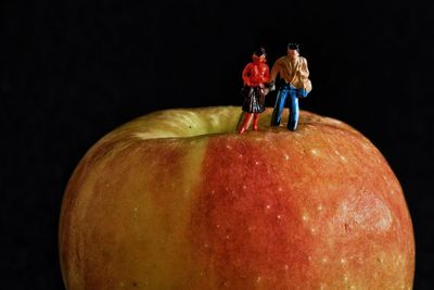 Close-up of figurines on apple against black background