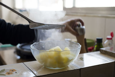 Close-up of spatula over glass bowl with food on table at home