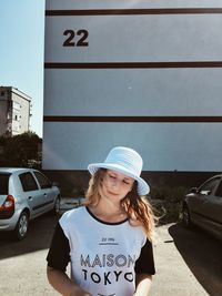 Woman wearing hat while standing against building