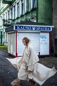 Side view of a woman sitting in front of building