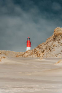 Lighthouse by sea against sky