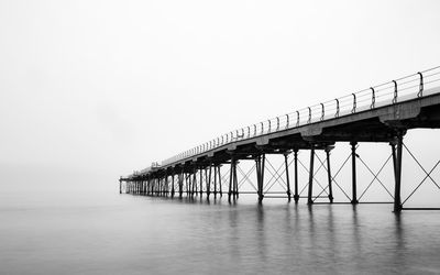 Bridge over calm sea against clear sky