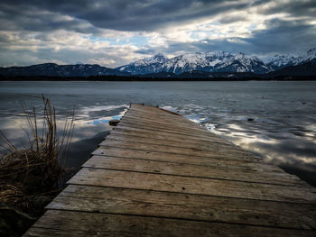 Scenic view of lake by snowcapped mountains against sky