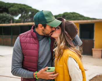 Rear view of man and woman using phone while standing in winter