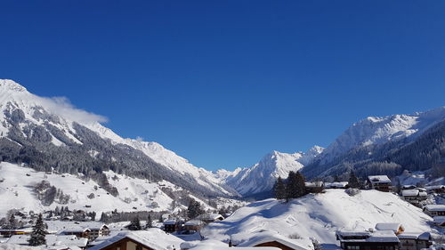 Scenic view of snowcapped mountains against clear blue sky