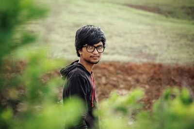 Young man looking away while standing on land