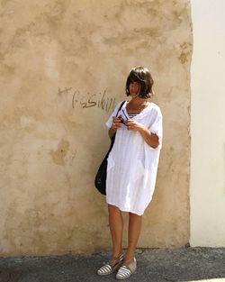 Full length of woman standing against wall