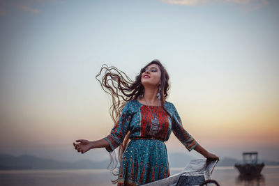 Full length of woman standing against sky during sunset