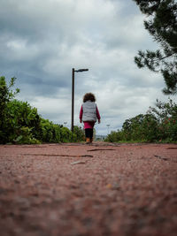 Rear view of woman standing by plants against sky