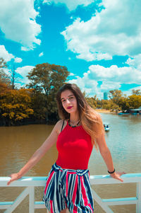 Portrait of beautiful young woman standing against sky