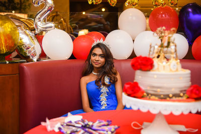 Portrait of woman with balloons at table