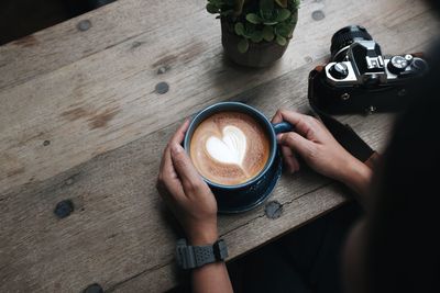 High angle view of woman holding coffee cup on table