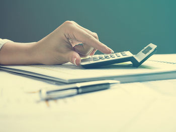 Cropped hands of businesswoman using calculator with documents at desk