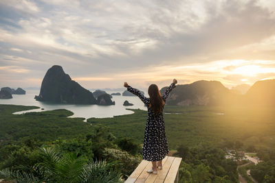 Woman standing on mountain against sky during sunset